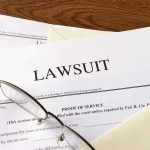 Documents labeled Lawsuit with glasses on top