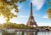 Eiffel Tower in Paris with boats on the river and green trees