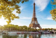 Eiffel Tower in Paris with boats on the river and green trees