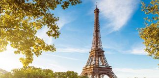 Eiffel Tower in Paris with boats on the river and green trees