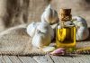 A bottle of olive oil surrounded by garlic cloves on a burlap background