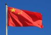 Chinese national flag waving against a clear blue sky