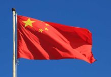 Chinese national flag waving against a clear blue sky