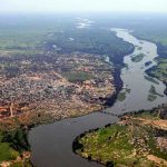 Aerial view of a river winding through a town and green fields