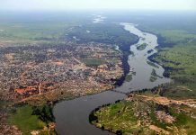 Aerial view of a river winding through a town and green fields