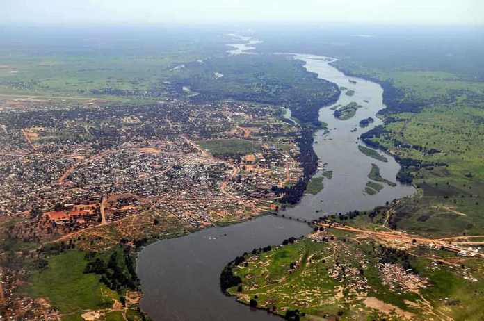 Aerial view of a river winding through a town and green fields