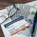 Trump SLASHES Drug Costs – Healthcare Earthquake! Medicare card glasses pen money on wooden table