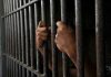 Prison Guards MURDER Inmate — Brutal ATTACK Hands gripping prison cell bars tightly.