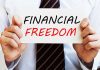 A man in a business suit holding a sign that says Financial Freedom