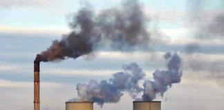 Industrial plant emitting black smoke into the sky.