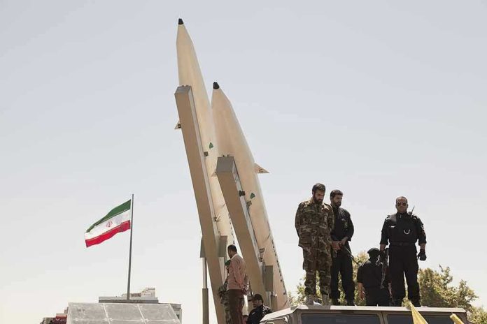 681421708 Military personnel beside missiles and Iranian flag.