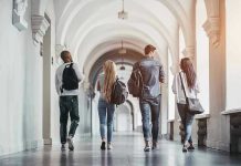 AI Cheating Wave ROCKS Top University! Four students walking in a corridor together.
