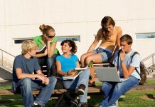 Teens Sue Government — Social Media Ban BLOCKED? Group of students sitting on a bench outdoors, engaged in study and discussion