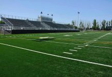 Explosive NCAA Probe: Disgraced Coach Stands Strong Amid Rumors Empty football field with bleachers in background.