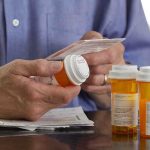 Person holding a prescription bottle and reading medical instructions