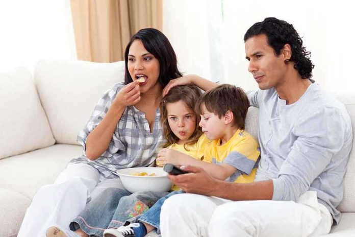 shutterstock_46386244.jpg A family of four enjoying a movie night on the couch with snacks