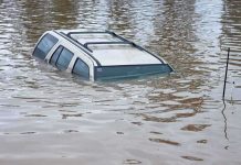 A partially submerged vehicle in floodwaters