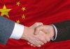 Two hands shaking in front of the Chinese flag