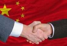 Two hands shaking in front of the Chinese flag