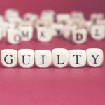 Dice spelling GUILTY on a red surface.