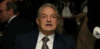 Elderly man in a suit sitting at a dining table during a formal event