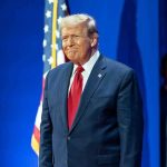 Catholic Teacher FIRED After Sick Trump Fantasy Leaked Man in suit next to American flag.