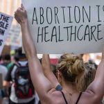 University Under Fire For Hosting ‘Abortion Doula For Teenagers Protestors holding signs about womens rights and healthcare.