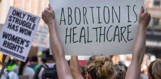 University Under Fire For Hosting ‘Abortion Doula For Teenagers Protestors holding signs about womens rights and healthcare.