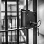 Trans Inmate Transferred After Impregnating Too Many Woman Jail cell door with key in lock.