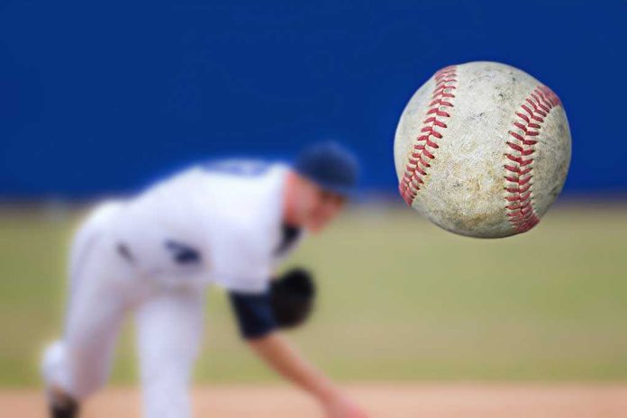 A baseball in mid-air with a pitcher in the background preparing to throw