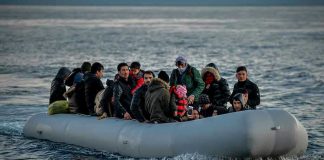 People on a packed raft in open water.