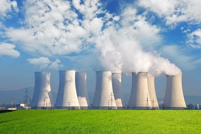 Nuclear power plant with cooling towers emitting steam against a blue sky