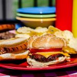 Backyard BBQ Battle Erupts Over Fire Risk A plate with a hamburger, hot dog, and potato chips on a picnic table