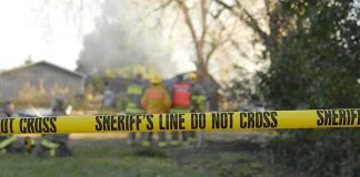 Alligator Accident EXPOSED as Brutal Murder! Yellow police tape marking a restricted area at a fire scene with firefighters in the background