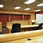 Vindictive Prosecution Drama: Case Dismissed Interior view of an empty courtroom with wooden furniture and American flags