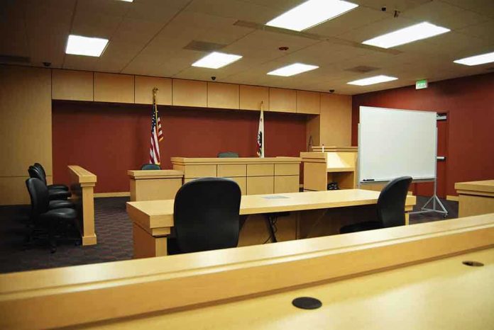 shutterstock_6768826-2 Interior view of an empty courtroom with wooden furniture and American flags