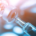 Close-up of a syringe drawing liquid from a vial