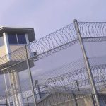Guard tower behind barbed wire fence in a prison.