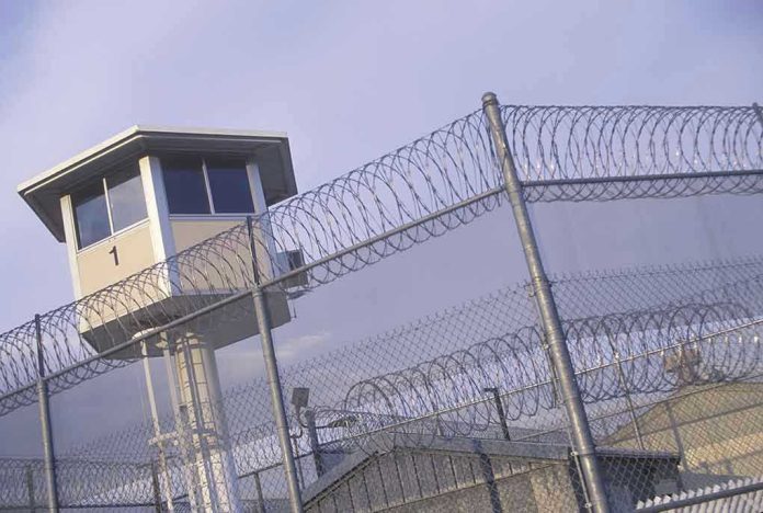 Guard tower behind barbed wire fence in a prison.