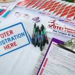 Voter registration table with forms, pens, and brochures.