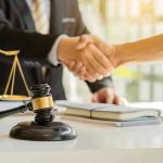 FOREVER BARRED: Top Law Enforcer Draws Fire Over Prison Hands shaking over legal documents with gavel and scales.
