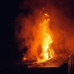 Building engulfed in large flames at night.