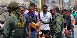 Crime Panic Redraws Latin America Border patrol agents inspecting group of individuals in line.