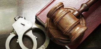 Handcuffs beside a gavel on a book.