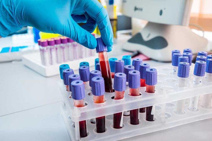 327930536 Gloved hand handling blood samples in a laboratory.