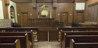 Fight Over Hidden Files Intensifies Interior view of an empty courtroom with wooden benches and a judges bench