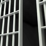 Families Blocked, Then Guards Open Doors Close-up view of metal prison bars in a dark environment