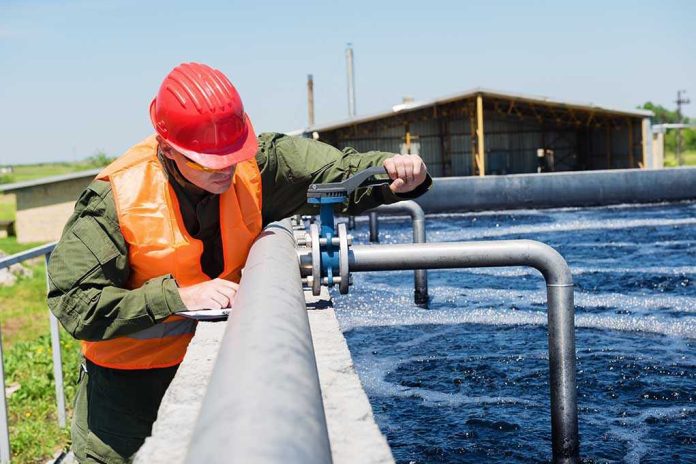 197223314 Worker inspecting water treatment plant pipes.