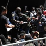 Crowd of people near police officer holding papers