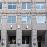 Tourist With Return Ticket Home Dies US government building facade with flags and number 500
